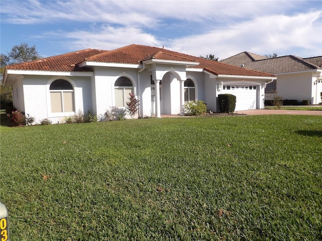 mediterranean / spanish house with a garage and a front lawn