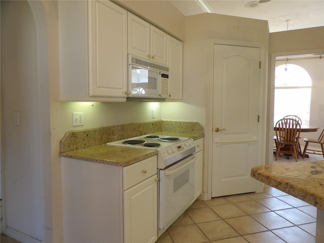 kitchen featuring light tile patterned flooring, white appliances, and white cabinets