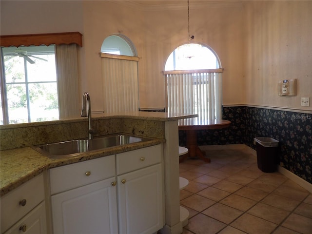 kitchen with light stone counters, sink, white cabinets, and light tile patterned flooring