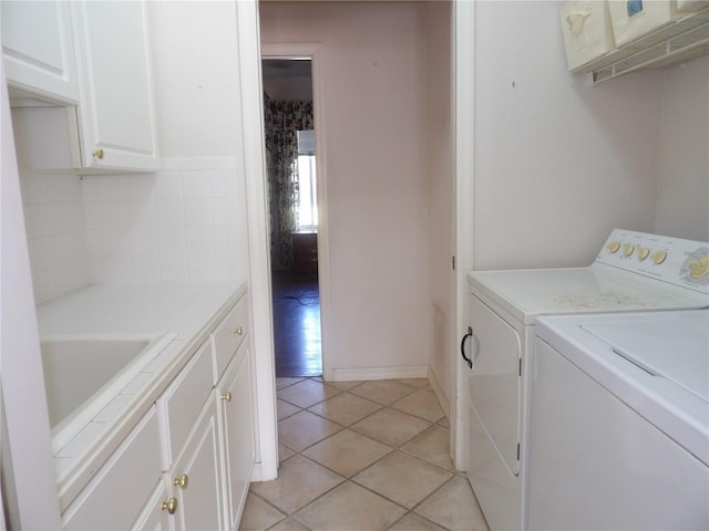 washroom with light tile patterned flooring, cabinets, sink, and washer and dryer