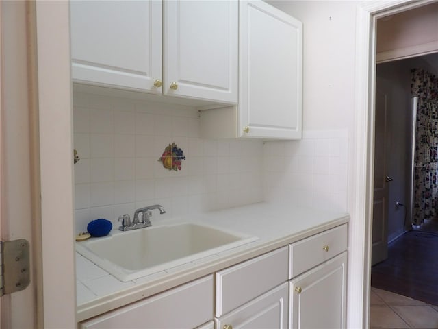 kitchen featuring white cabinetry, sink, light tile patterned flooring, and backsplash