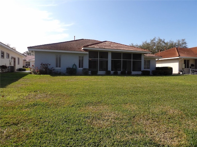 rear view of house featuring a yard and a sunroom