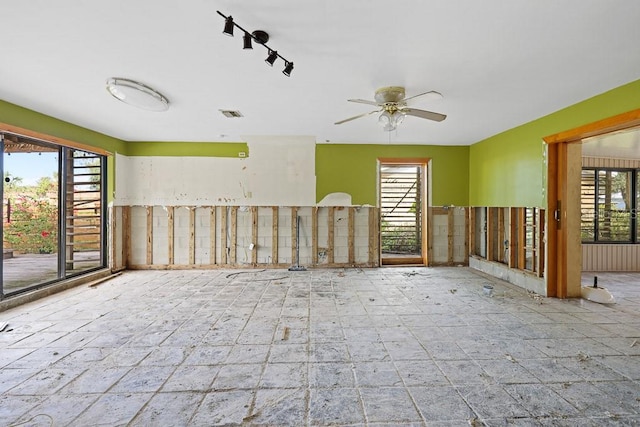 empty room featuring ceiling fan, rail lighting, and a healthy amount of sunlight