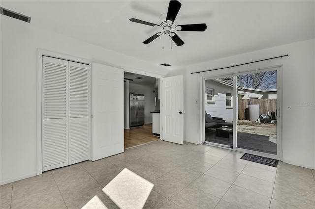 unfurnished bedroom featuring light tile patterned floors, stainless steel fridge, ceiling fan, access to outside, and a closet