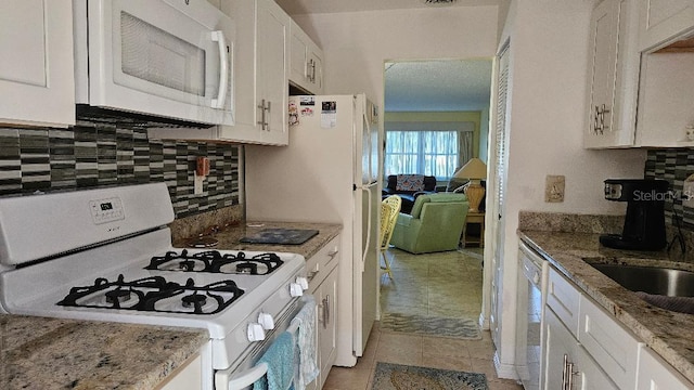 kitchen with tasteful backsplash, white appliances, white cabinetry, and light stone countertops