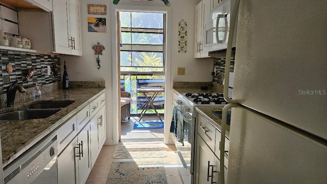 kitchen with decorative backsplash, stone countertops, white cabinetry, a sink, and white appliances