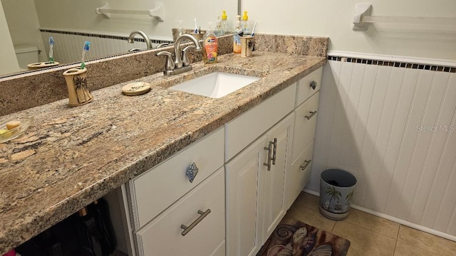 bathroom with radiator heating unit, wainscoting, tile patterned flooring, and vanity