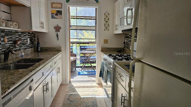 kitchen featuring backsplash, white cabinets, a sink, and white appliances