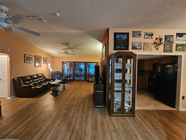 living room featuring hardwood / wood-style flooring, vaulted ceiling, ceiling fan, and a textured ceiling