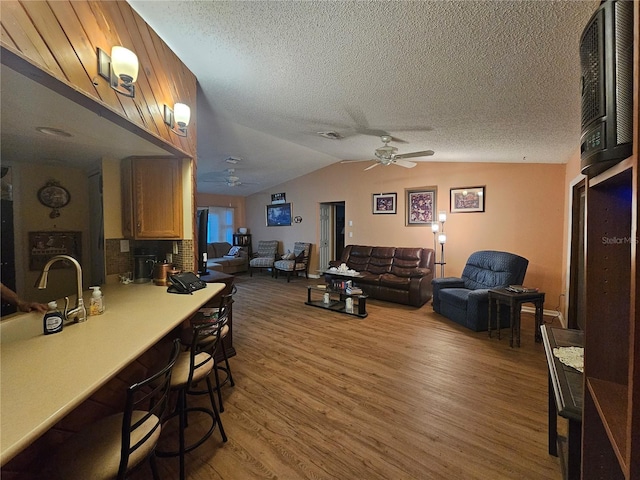 living room with ceiling fan, wood-type flooring, a textured ceiling, and lofted ceiling