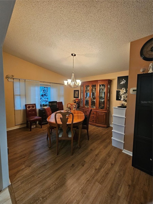 dining space with dark hardwood / wood-style flooring, a textured ceiling, lofted ceiling, and a chandelier