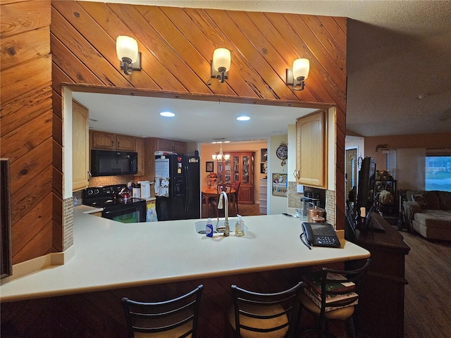 kitchen featuring a kitchen bar, kitchen peninsula, sink, and black appliances