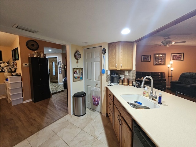 kitchen featuring black dishwasher, sink, decorative backsplash, ceiling fan, and light wood-type flooring