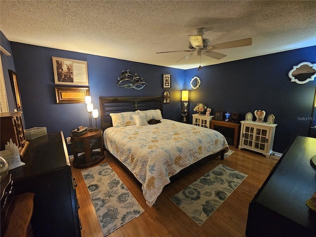 bedroom with hardwood / wood-style flooring, a textured ceiling, and ceiling fan