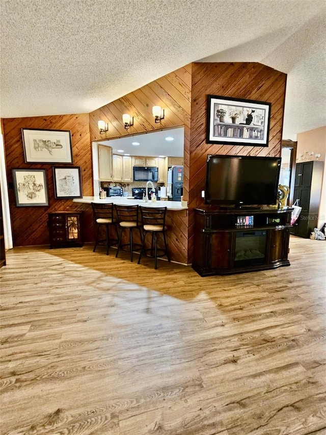 7711 Innis Ct, Saint Petersburg, FL 33709 - interior space featuring a textured ceiling, black appliances, wooden walls, and light wood finished floors