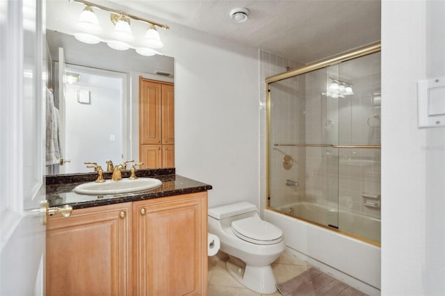 full bathroom featuring tile patterned flooring, bath / shower combo with glass door, vanity, and toilet