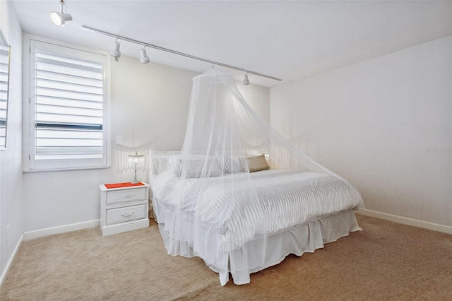 bedroom featuring track lighting and light carpet