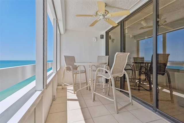 sunroom with a water view and ceiling fan