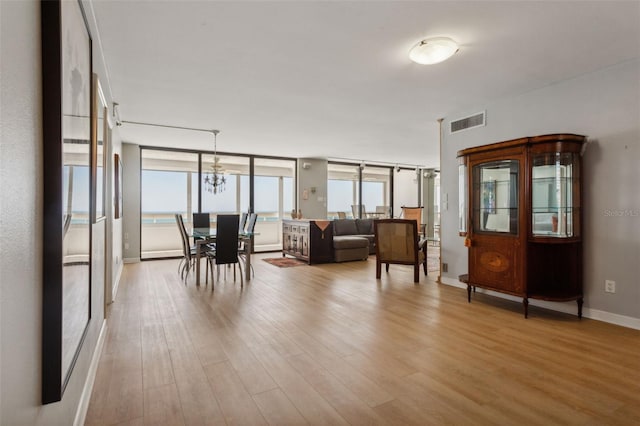 living room featuring a notable chandelier, a wall of windows, and light hardwood / wood-style floors