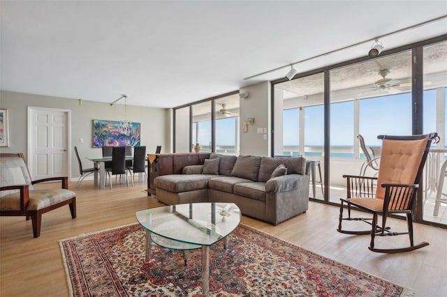 living room featuring floor to ceiling windows, a water view, and light hardwood / wood-style flooring