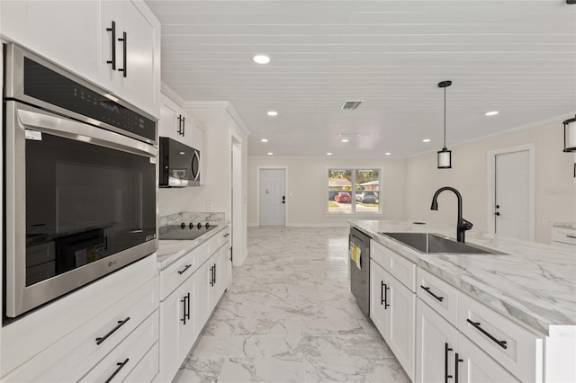 kitchen featuring sink, light stone counters, decorative light fixtures, appliances with stainless steel finishes, and white cabinets