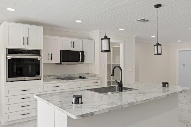 kitchen featuring white cabinets, stainless steel appliances, hanging light fixtures, and a center island with sink