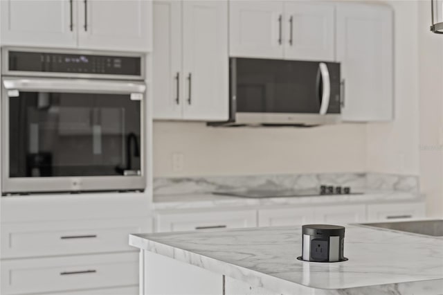 kitchen featuring appliances with stainless steel finishes, white cabinets, and light stone counters