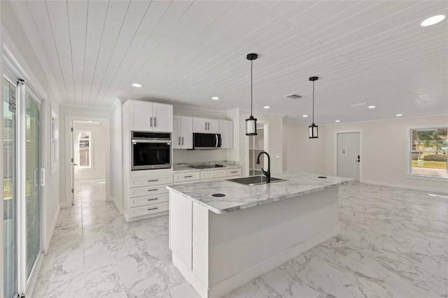 kitchen with pendant lighting, white cabinetry, sink, a kitchen island with sink, and stainless steel appliances