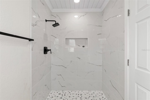 bathroom with ornamental molding and tiled shower