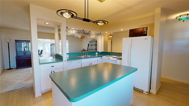 kitchen featuring sink, a center island, kitchen peninsula, white appliances, and white cabinets