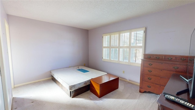 bedroom featuring light carpet and a textured ceiling