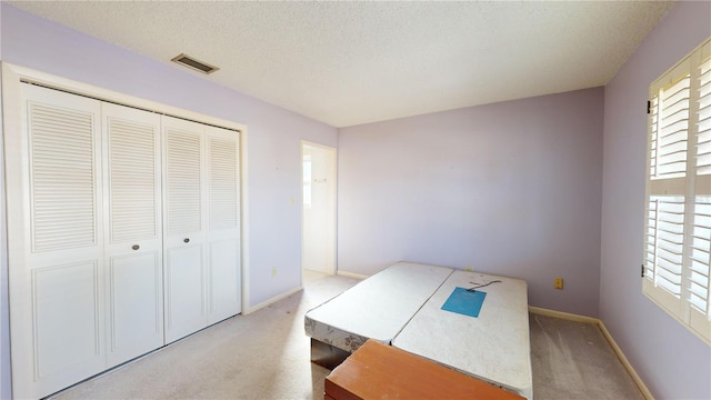 unfurnished bedroom with carpet floors, a textured ceiling, and a closet