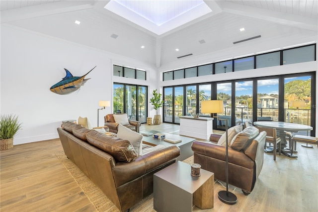 living room with a high ceiling, light hardwood / wood-style floors, and beamed ceiling