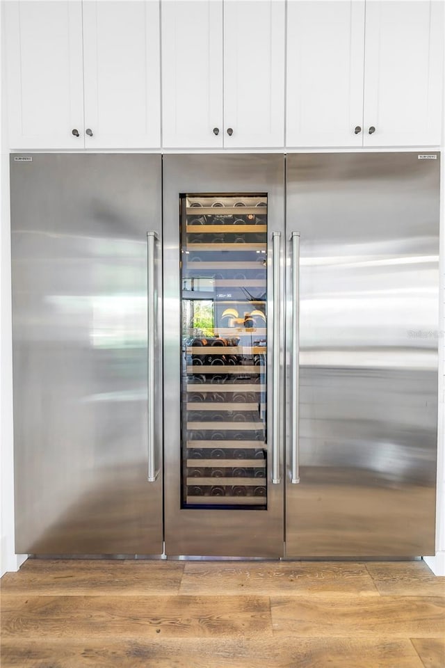 room details featuring white cabinetry, beverage cooler, and light hardwood / wood-style floors