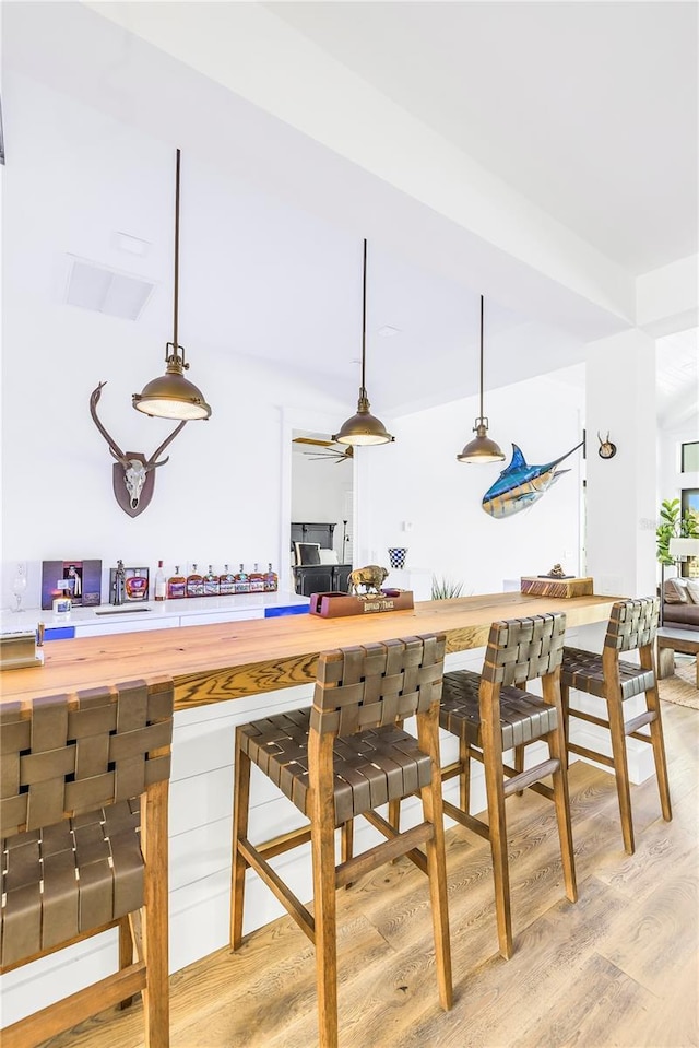 bar with pendant lighting, wood counters, and light wood-type flooring