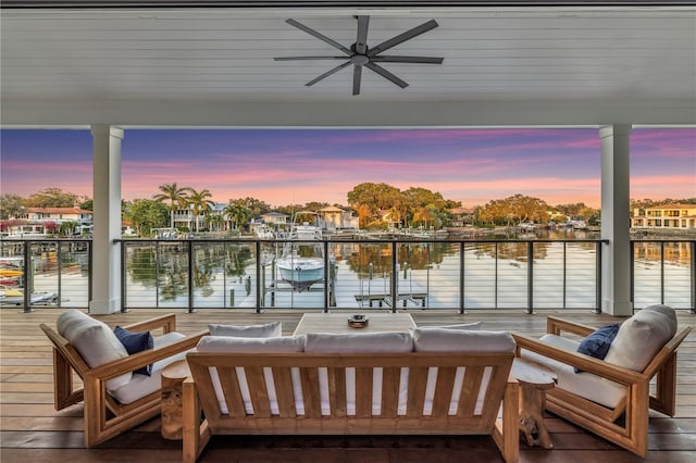 balcony at dusk featuring outdoor lounge area, ceiling fan, and a water view