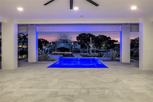 pool at dusk featuring ceiling fan