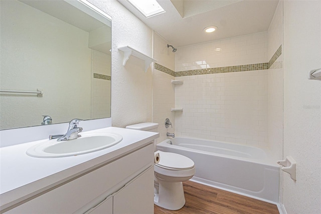 full bathroom featuring vanity, hardwood / wood-style floors, tiled shower / bath combo, and toilet