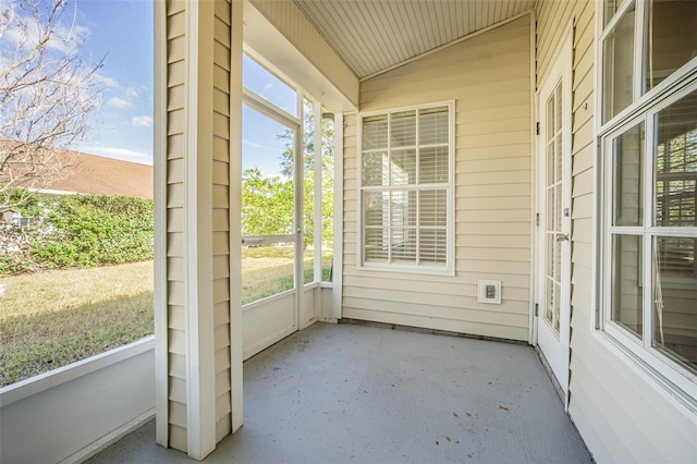 unfurnished sunroom featuring vaulted ceiling and plenty of natural light