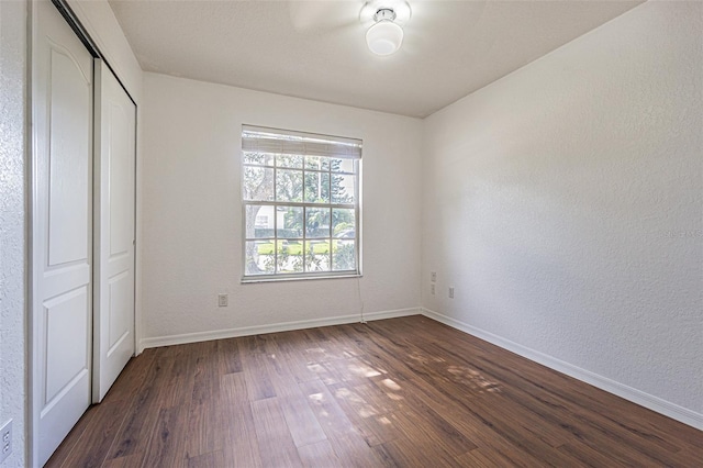 unfurnished bedroom with dark hardwood / wood-style floors and a closet