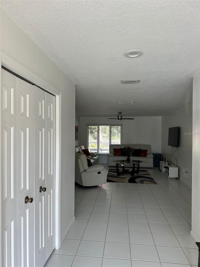 living room with ceiling fan, a textured ceiling, and light tile patterned floors