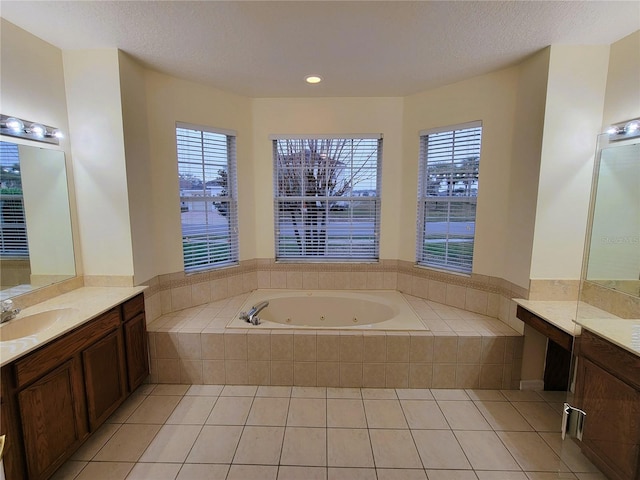 bathroom with a textured ceiling, vanity, plenty of natural light, a relaxing tiled tub, and tile patterned flooring