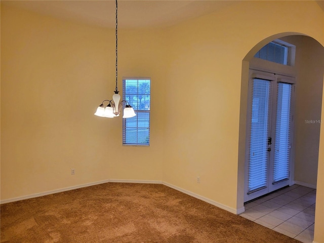 spare room with tile patterned flooring and an inviting chandelier