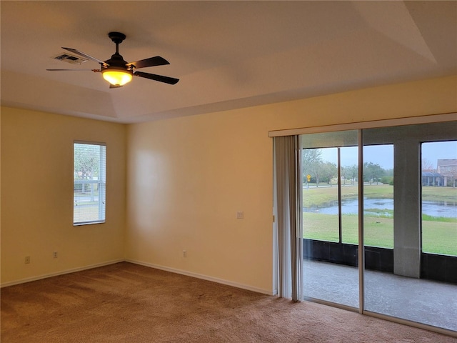 carpeted empty room with ceiling fan and a water view