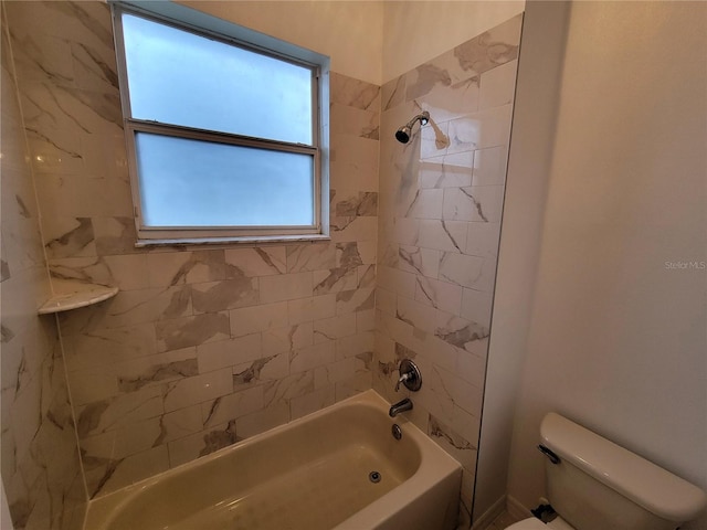 bathroom featuring tiled shower / bath combo and toilet