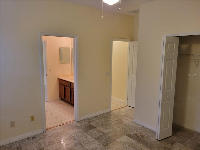 unfurnished bedroom with ensuite bathroom and a closet