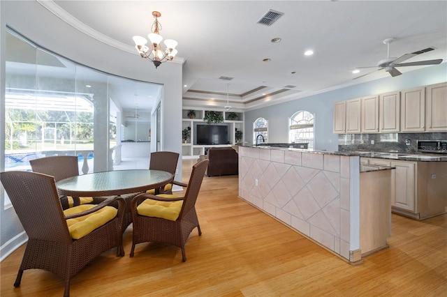 kitchen with hanging light fixtures, crown molding, ceiling fan with notable chandelier, and light hardwood / wood-style floors