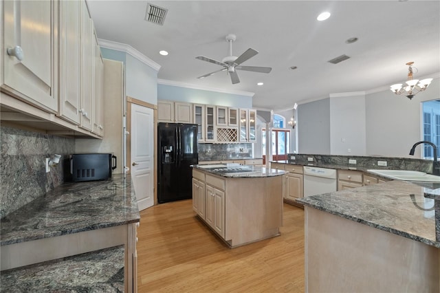 kitchen featuring sink, stone countertops, hanging light fixtures, a kitchen island, and black appliances