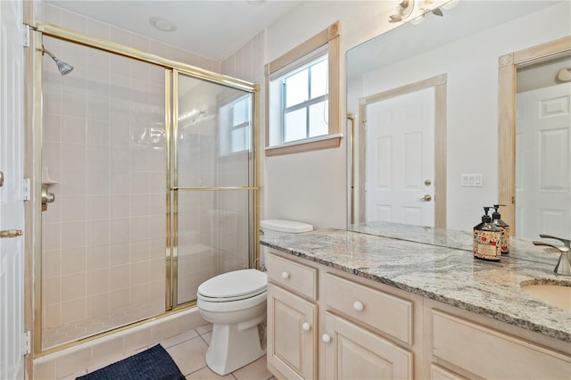 bathroom with toilet, vanity, a shower with door, and tile patterned flooring