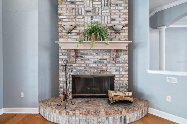 interior details with hardwood / wood-style flooring, ornamental molding, a fireplace, and decorative columns